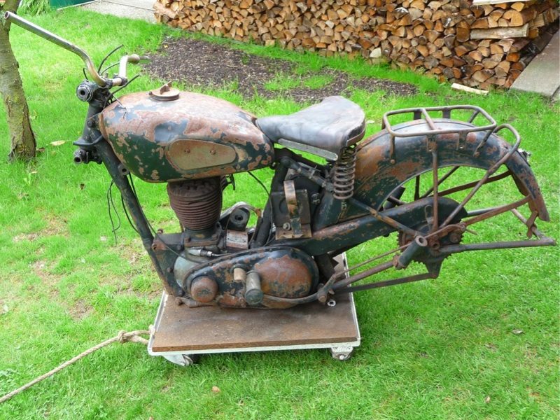 Left side of the incomplete and rusted BSA KM21 on a wheeled platform outdoors.