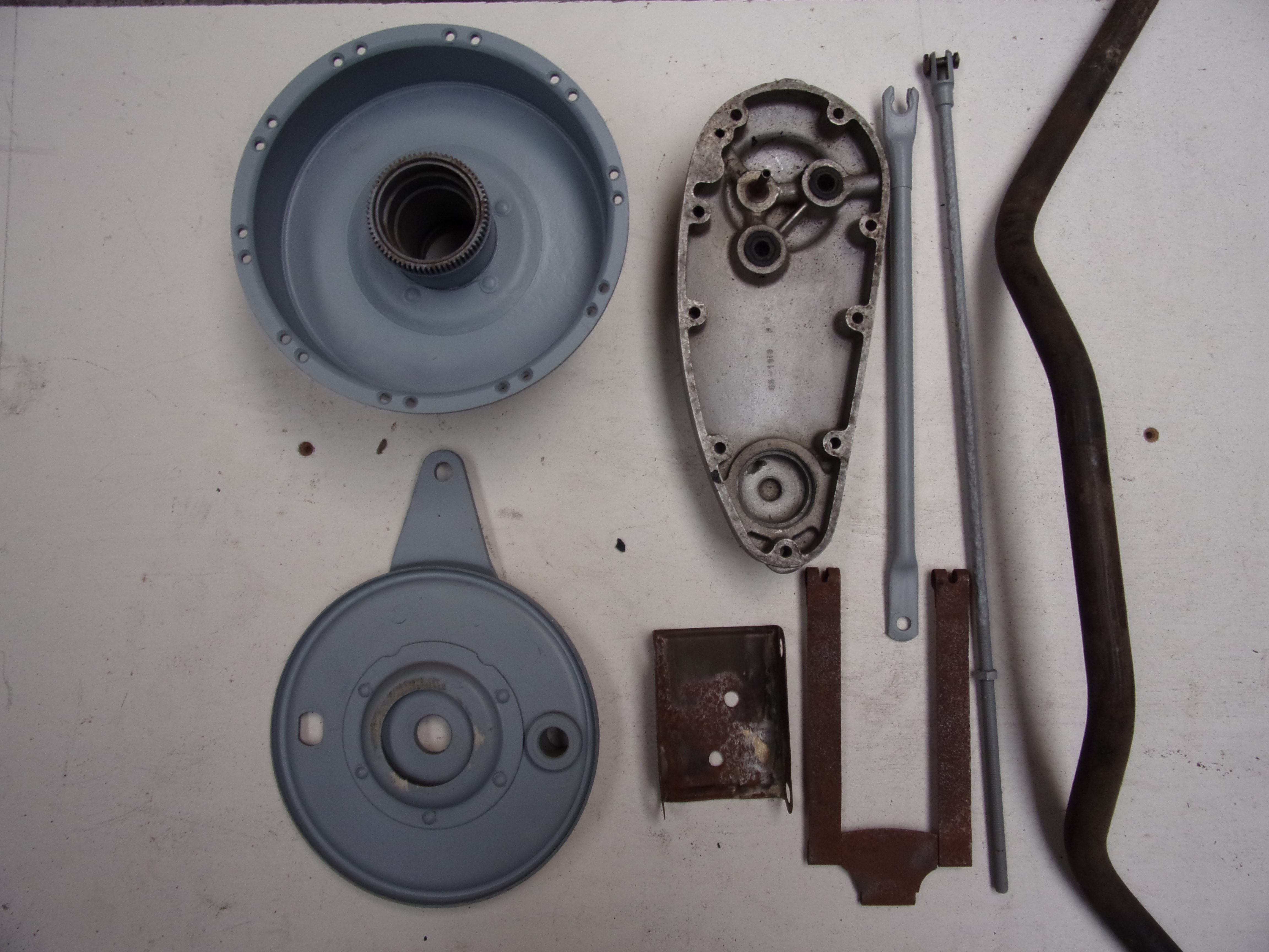 Brake plates, stays and other motorcycle components arranged for inspection.