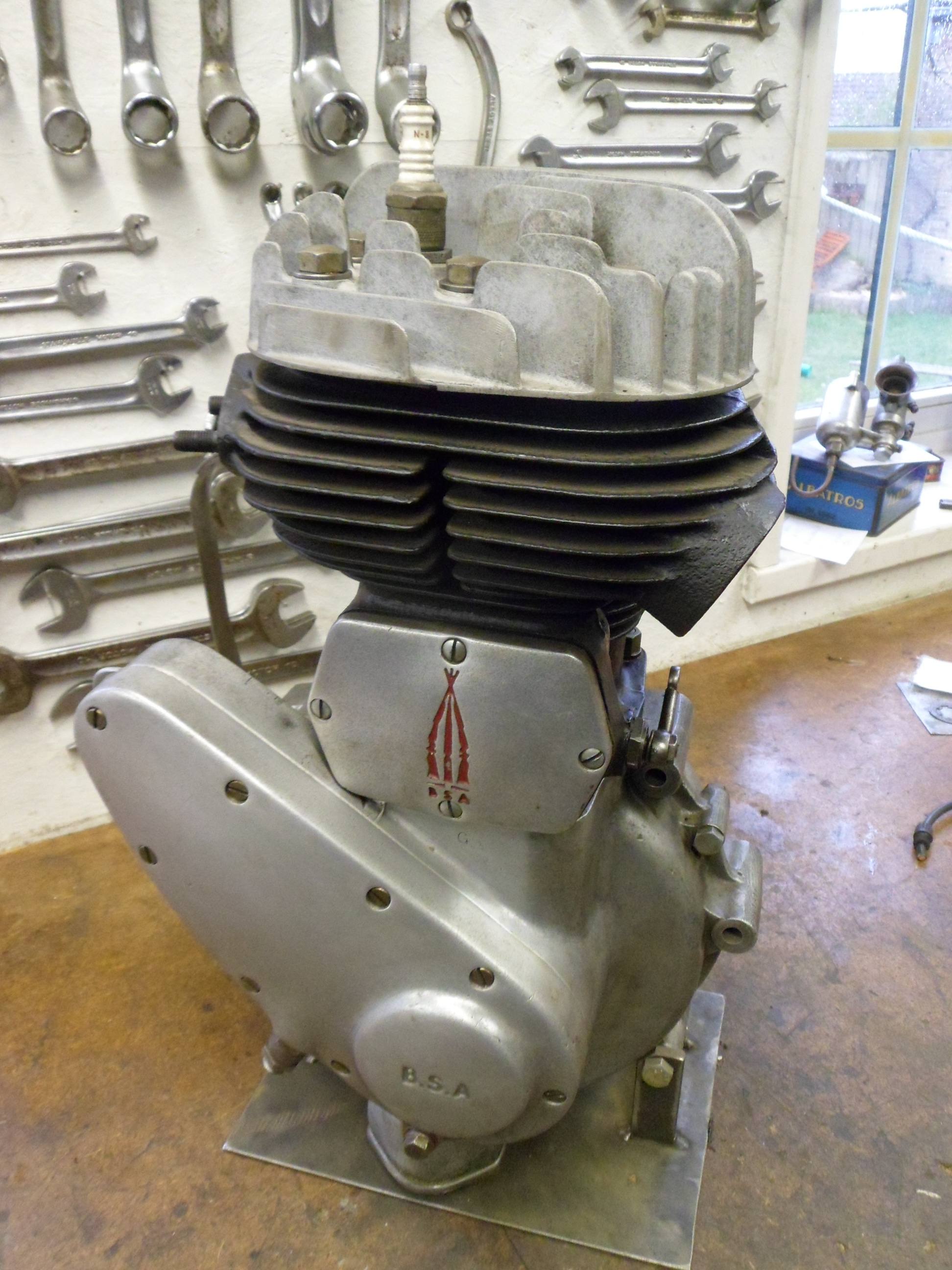 Complete BSA single-cylinder engine standing on a metal base in a workshop.