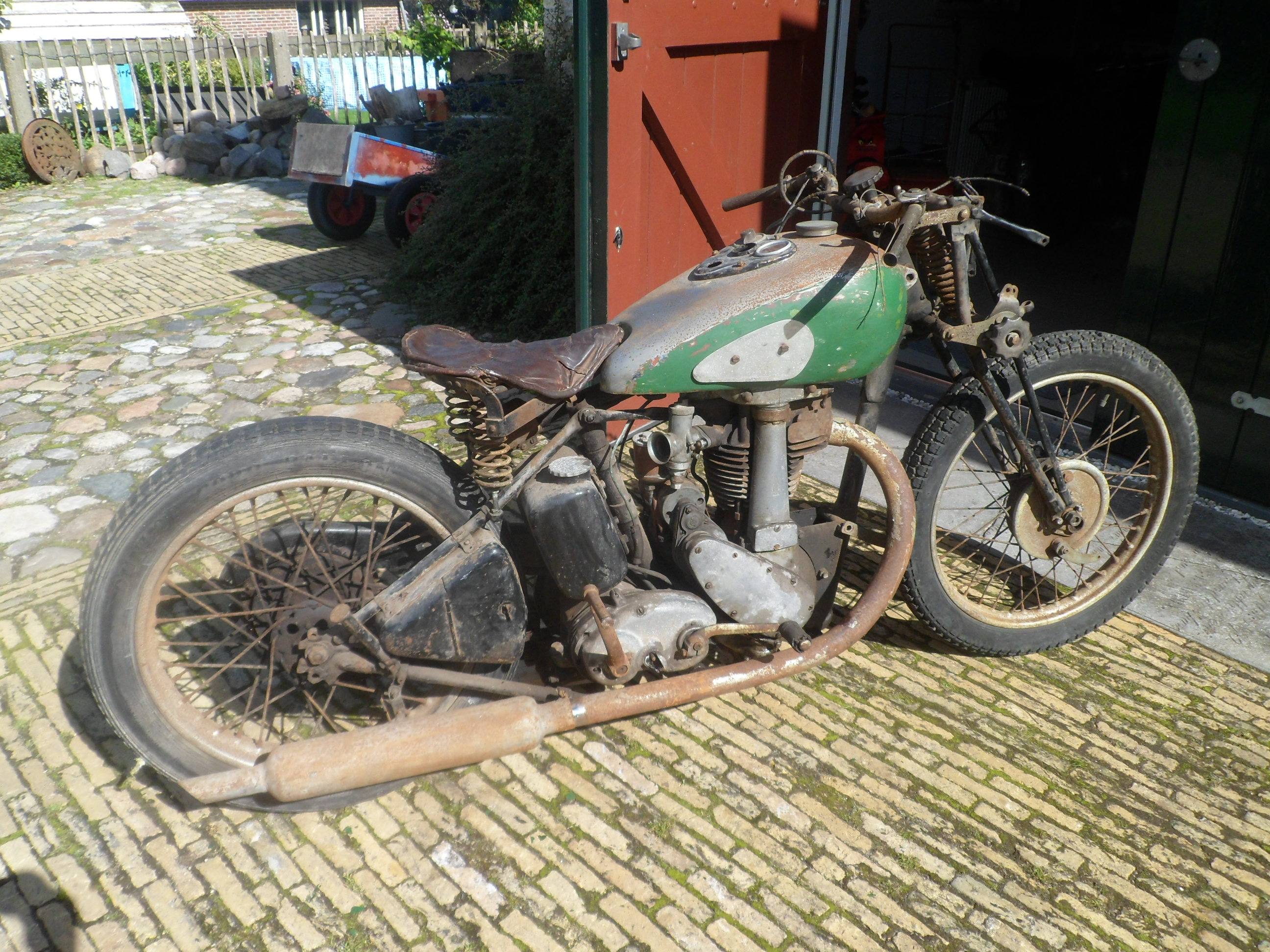 Incomplete BSA M23 Empire Star with green and silver fuel tank outside a workshop.